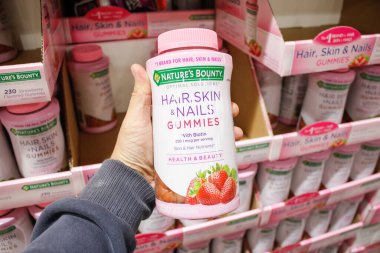 Alhambra, California/United States - 02/19/2020: A hand holds a container of Nature's Bounty Hair, Skin, & Nails Gummies, on display at a local big box grocery store.