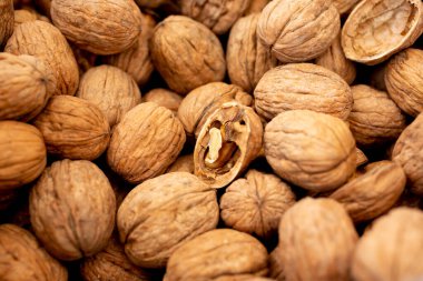 A view of a bin full of walnuts, with one opened half walnut in the center of the frame.