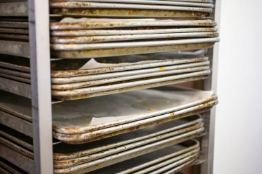 Pasta tepsisiyle dolu bir rafın manzarası, bir fırın ortamında.