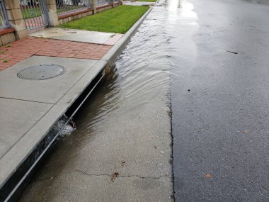 A view of excess rain water flowing towards a neighborhood draining system.