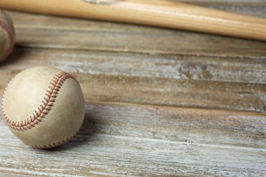 A view of a vintage baseball and wooden bat on a wood surface, as a background.