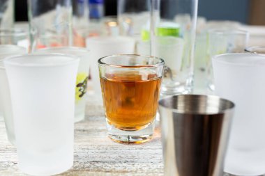 Ahşap bir masa yüzeyindeki birkaç boş kadehin görüntüsü. Ortasında bir kadeh, içinde de alkol var..