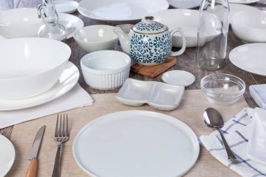 A view of a restaurant dinner place setting filled with empty dishes on a table, in a still life setting.