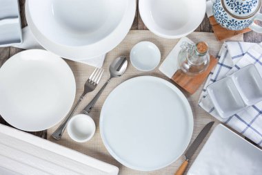 A top down view of a dining table place setting, featuring an array of clean empty dinnerware.