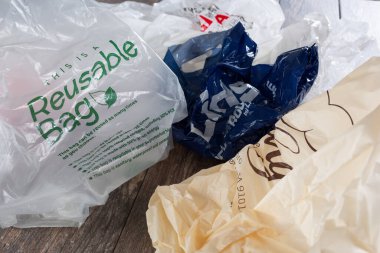 Los Angeles, Kaliforniya / ABD - 04 / 30 / 2020: Tahta bir yüzey üzerinde yeniden kullanılabilir bir torba içeren çok sayıda plastik torba manzarası.