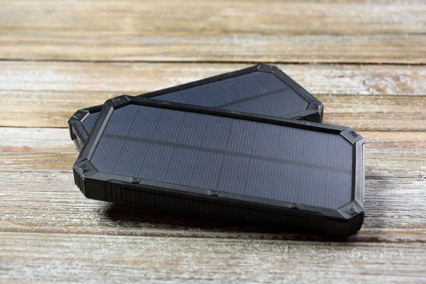 A closeup view of solar powered cell phone chargers on a wooden surface.