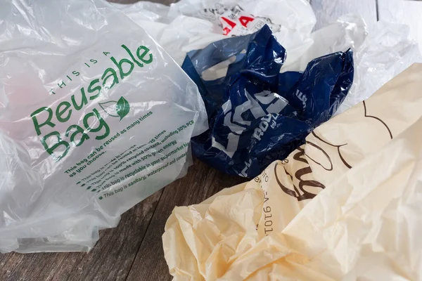 Los Angeles, Kaliforniya / ABD - 04 / 30 / 2020: Tahta bir yüzey üzerinde yeniden kullanılabilir bir torba içeren çok sayıda plastik torba manzarası.