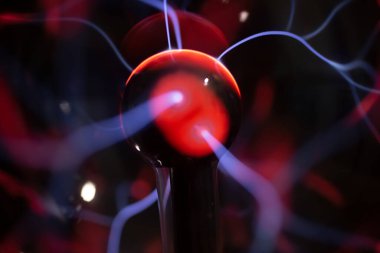 A closeup view of the sphere and glowing electricity emitted from a plasma ball lamp, as a background.