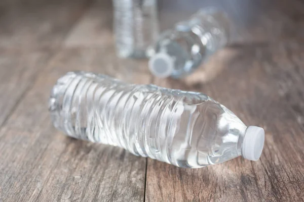 A view of three plastic water bottles with no label, on a wooden surface.