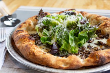 Köy pizzası manzarası, içinde mantar ve yeşillik gibi malzemeler var..