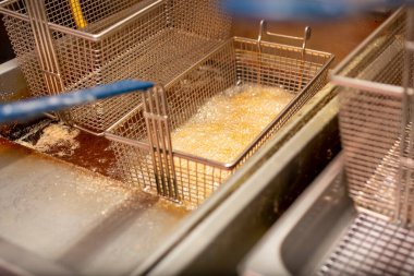 Lokanta mutfağında kızgın yağ ve yağda kızaran ve kaynayan bir sepet yiyecek manzarası..