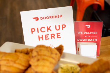 Los Angeles, CaliforniaUnited States - 02-24-2021: A view of a DoorDash pick up here sign on a table, and food in the foreground.