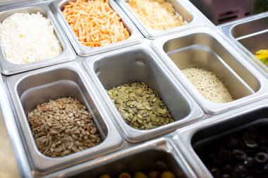 Ayçekirdeği, kabak tohumu, kenevir tohumu ve öğütülmüş sütsüz peynirlerden oluşan bir malzeme teşhir istasyonunun yakın plan görüntüsü..