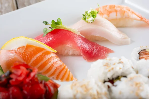 Somon, ton balığı, sarı kuyruk ve karides gibi nigiri içeren bir tabağın yakından görüntüsü..