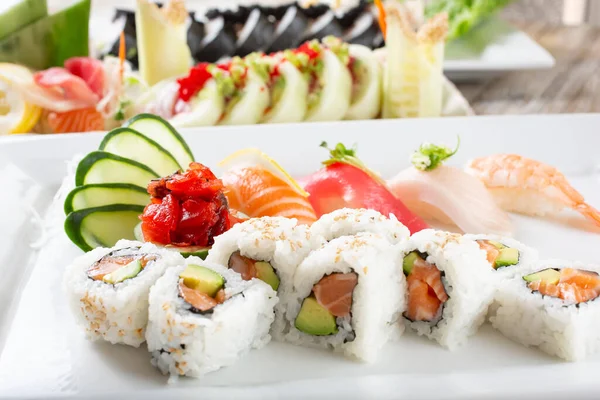 Somonlu avokado dilimli bir tabak ve arka planda daha çok suşi rulosu olan çeşitli nigiri..