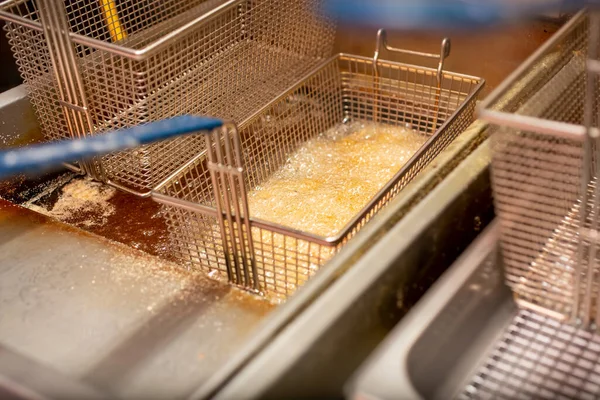 Lokanta mutfağında kızgın yağ ve yağda kızaran ve kaynayan bir sepet yiyecek manzarası..