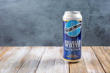 Los Angeles, Kaliforniya, ABD - 02-24-2021: Çerçevenin sağ tarafında, ahşap bir masa yüzeyinde uzun bir şişe Blue Moon birasının görüntüsü.