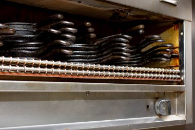 Lokanta mutfak ortamında görülen ızgara aletinin görüntüsü. Cihaz dökme demir tavalar dizisi için depolama olarak kullanılır.