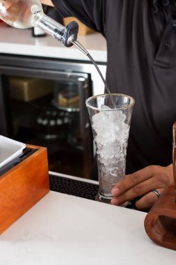 A view of a bartender pouring alcohol into a glass, in a restaurant or bar setting.