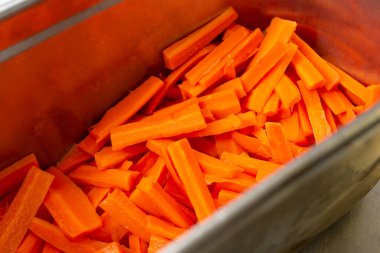 Kesik havuç çubuklarıyla dolu metal bir kap manzarası.