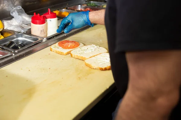 レストランのキッチンの準備ステーションでサンドイッチを準備料理人の肩のビュー — ストック写真