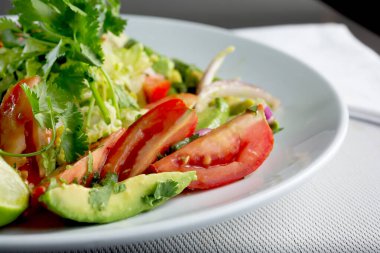 Domatesler, avokadolar ve kişniş filizlerinin yer aldığı bir bahçe salatasının yakın çekim görüntüsü..