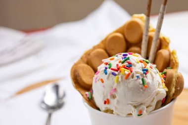 Bir tatlı fincanı manzarası, bir kepçe dondurma ve bir puf.