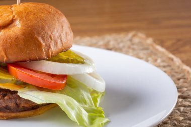 Tabakta çizburgerin yan görüntüsü. Hamburgerin bir kısmı çerçevenin solundan kesilmiş..