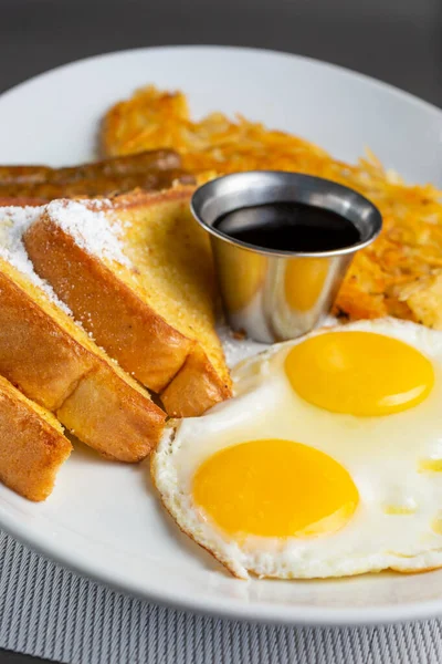 Kahvaltı tabağı manzarası, içinde yumurta, ekmek, sosis ve patates var..