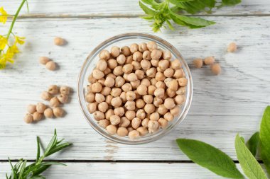 Kurumuş nohutlarla dolu bir kase dolusu sade ahşap masa yüzeyinin üstü..