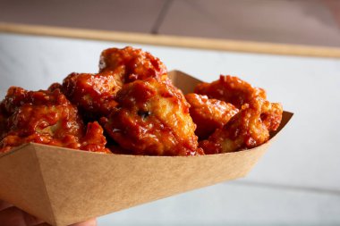 Asya soslu tavuk kanadı tepsisi tutan bir el görüntüsü..