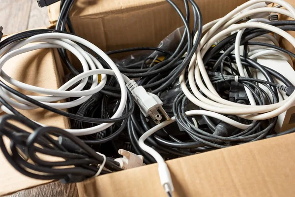 A view of a cardboard box full of computer and electronic cords.