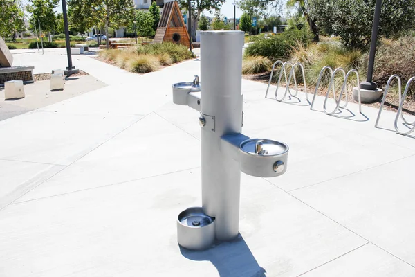A view of a modern water fountain with a drinking area close to the ground, good for pets, seen at a local park in Los Angeles.