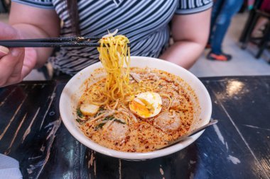 Kadınlar bulanık ahşap masada yumurtalı domuz etli erişte yiyorlar.