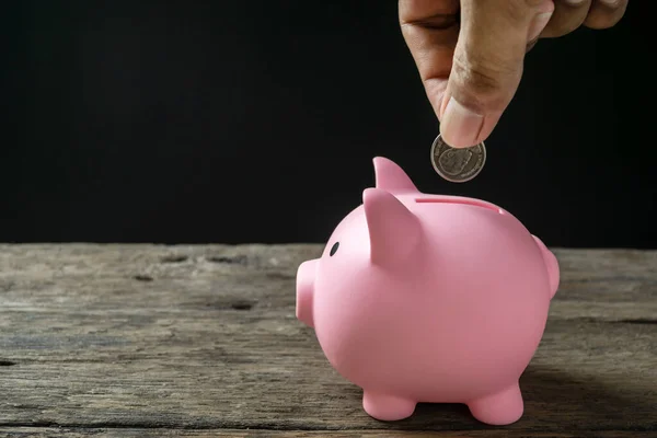 Save money and account banking for finance concept, Hand with coin on piggy bank blurred background