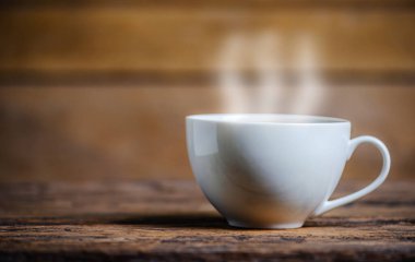 Bir fincan kahve, kahve çekirdeği ve ahşap arka planda koyu ton dtyle.