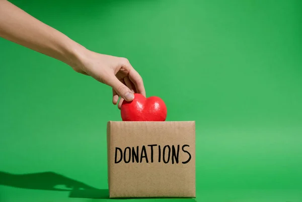 Hand Placing Heart Charity Donations Box Green Background — Stock Photo, Image