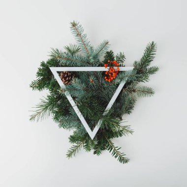 Noel üçgeni çerçevesi, her zaman yeşil olan doğal kış dalları ve parlak arkaplanda kırmızı böğürtlenlerden yapılmıştır. Düz yatıyordu. Asgari Noel ya da yeni yıl konsepti. Metin için yer.
