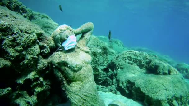 Socha v lékařské masce na dně moře a vedle ní několik ryb. — Stock video