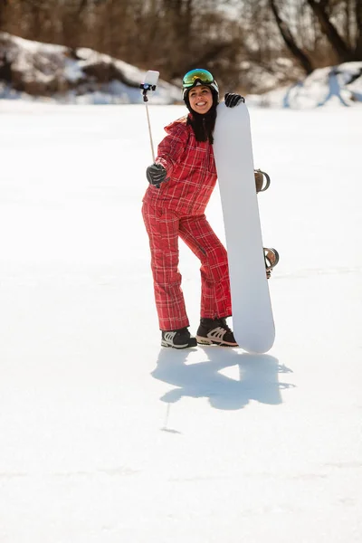 Frau mit Snowboard macht Selfie mit Smartphone am Stock — Stockfoto
