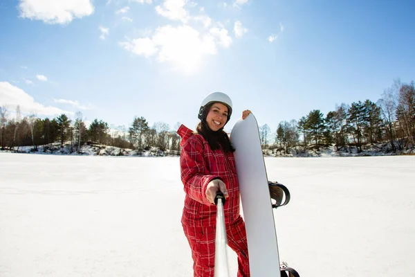 Vrouw met het snowboard met behulp van smartphone op een stok voor het maken van selfie — Stockfoto