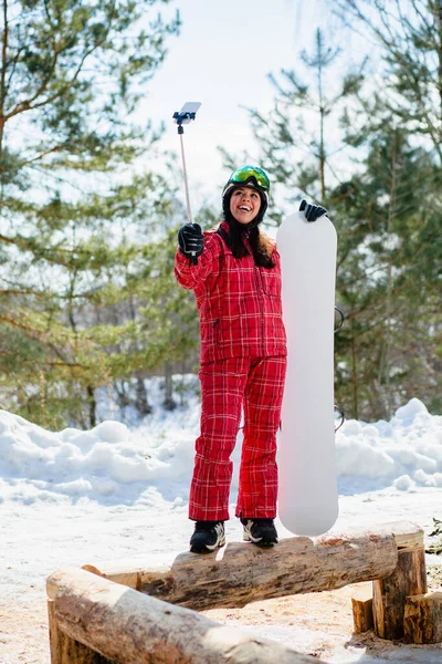Donna con lo snowboard utilizzando smartphone su un bastone per fare selfie — Foto Stock