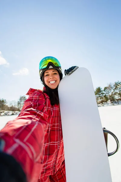 Vacker ung kvinna med snowboard gör selfie — Stockfoto