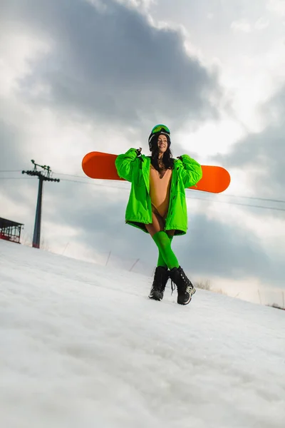 Молода красива жінка позує зі сноубордом на лижному схилі — стокове фото