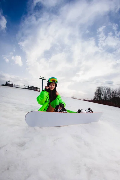 Joven hermosa mujer posando con una tabla de snowboard en una pista de esquí —  Fotos de Stock