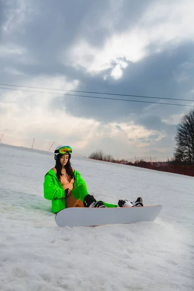 Junge schöne Frau posiert mit einem Snowboard auf einer Skipiste — Stockfoto