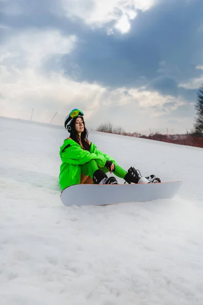 Giovane bella donna in posa con uno snowboard su una pista da sci — Foto Stock