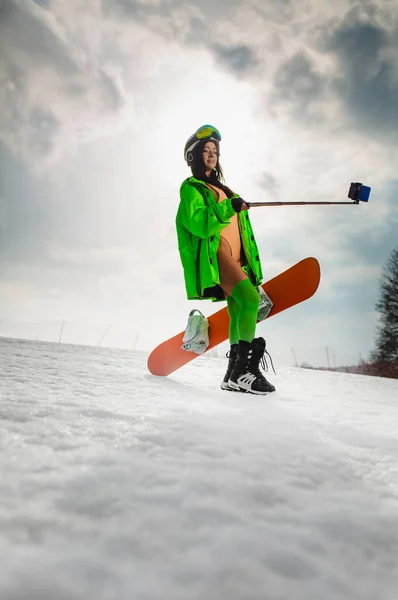 Schöne Frau macht mit Smartphone Selfie mit Snowboard auf der Skipiste — Stockfoto