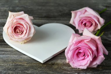Anneler Günü kartı. Beyaz tahta kalp şekilli dekorasyon ve pembe güller.