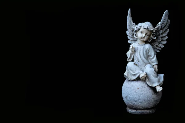 Condolence card with an angel figurine isolated on black background with copy space